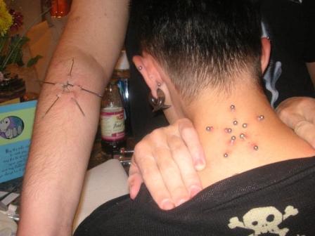 Guy showing his neck pierced with barbells in form of star and with pierced 