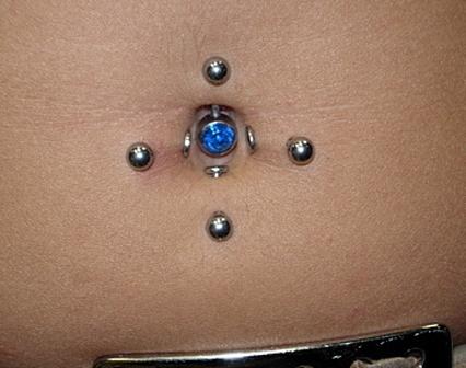 Blue colored jewel pierced on navel and barbells on stomach