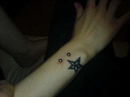 girly foot star tattoo. Barbells pierced on wrist along with a star tattoo