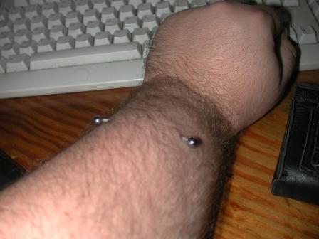 Wide Apart – Wrist Piercing. A man shows barbells pierced on his wrist