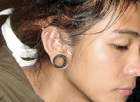 A girl showing her industrial and flesh tunnel in lobe ear piercing.