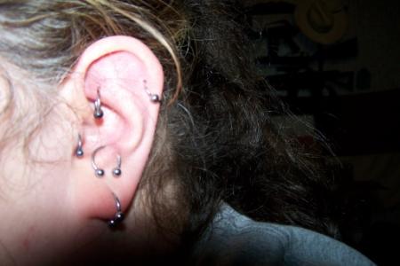 A woman showing her rook, helix, tragus, anti-tragus and lobe ear piercing.