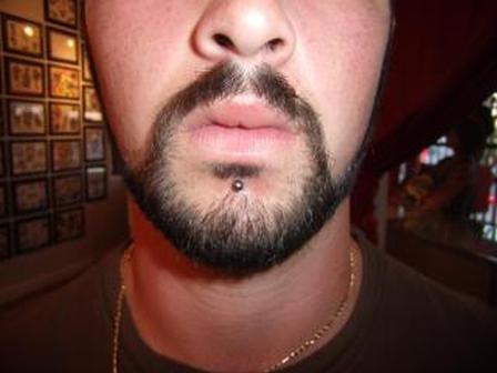 A guy with french cut showing his labret lip piercing.